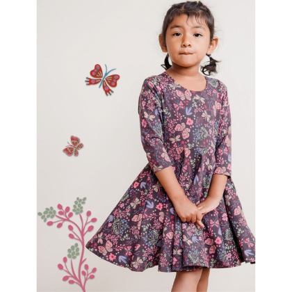 Girl standing in front of a wall with butterfly decals in a Mightly Twirl Dress