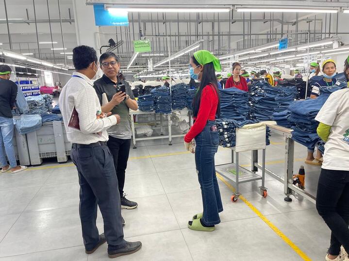 Heng Sreyneat, a Fair Trade Factory worker, talking with a group of people on the factory floor.